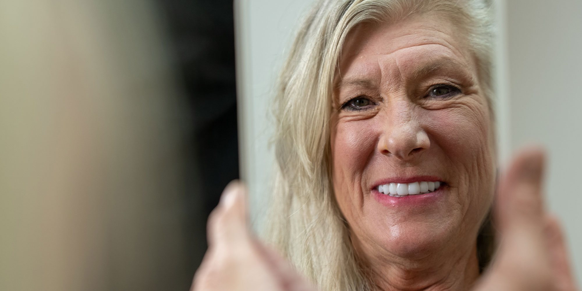 patient looking in the mirror smiling brightly after their dental implant treatment